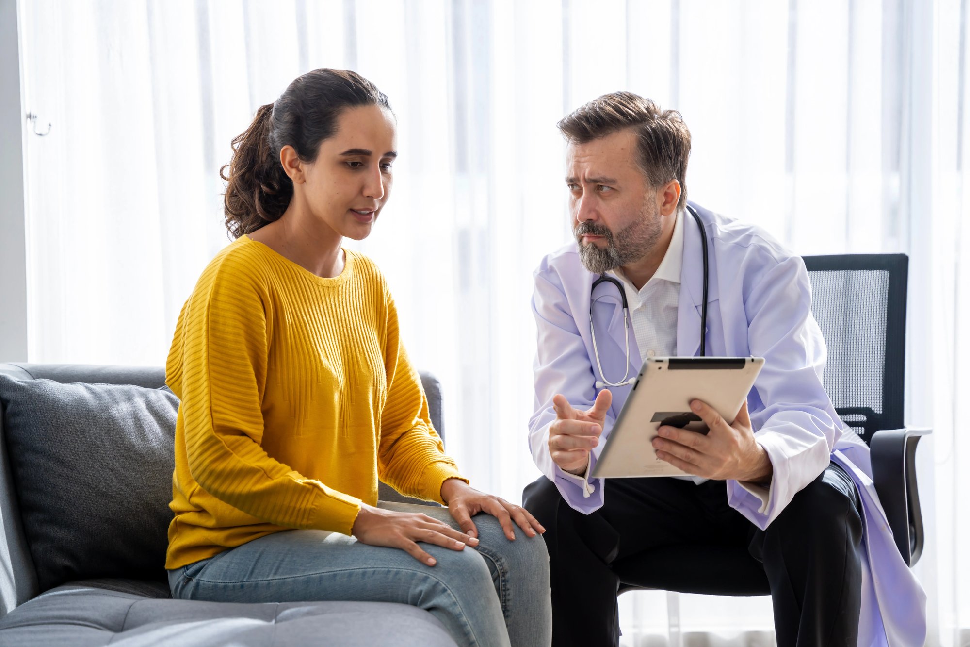 Doctor is sat talking to a woman giving a diagnosis during a health assessment.