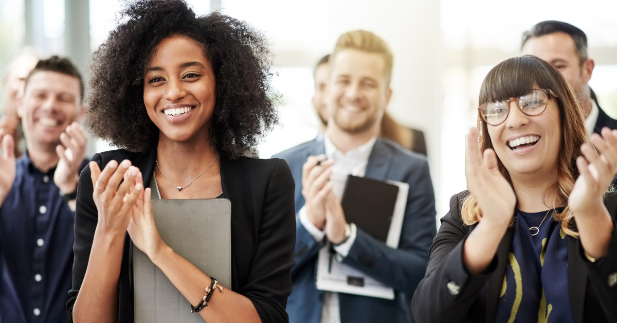 Employees applauding and looking happy at a meeting about their wellbeing benefits