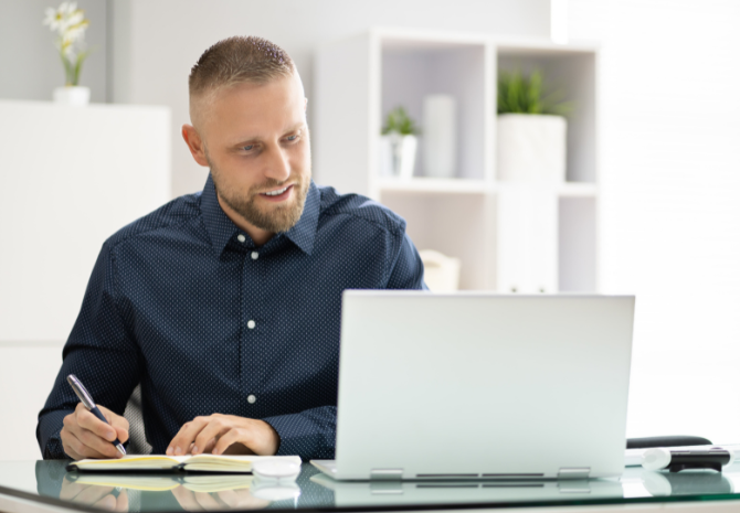 Man on a meeting looking happy as he notes down his estimated ROI on employee wellbeing benefits